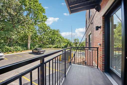 A black metal railing on a wooden deck overlooks a parking lot.