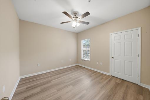 A room with a ceiling fan and a door.