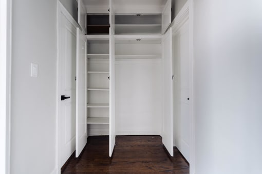 a closet with white walls and shelves and a wood floor