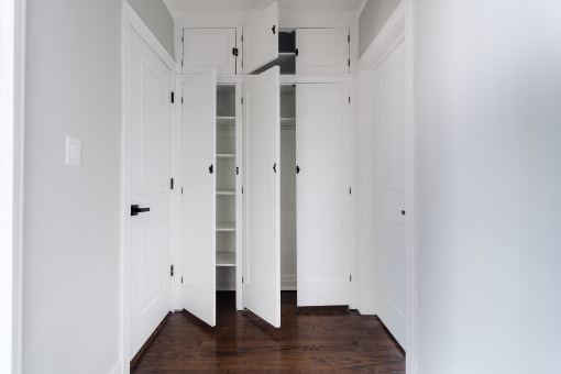 a row of white closet doors in a room with wood floors