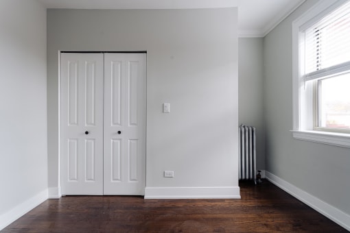 a room with two doors and a wood floor and a radiator