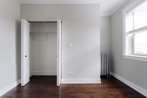 a room with a closet and a window and a wood floor