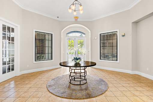 A large room with a round table in the middle and a chandelier hanging from the ceiling.