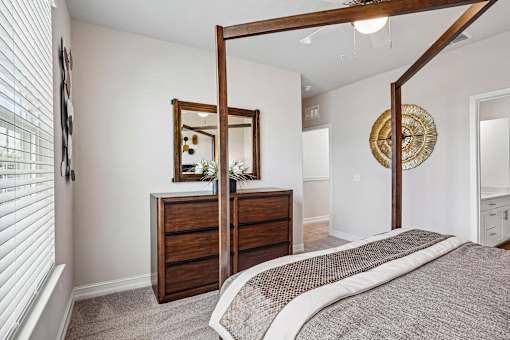 A bedroom with a large bed and a wooden dresser with a mirror above it.