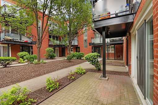 A brick building with a patio and bushes in front.
