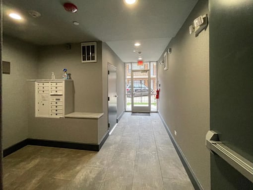 A long hallway with a white cabinet on the left and a door on the right.