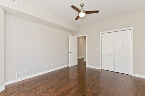A room with a ceiling fan and wood flooring.