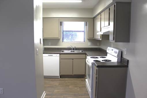 A kitchen with a white dishwasher and white oven.