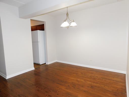 A room with wooden floors and a white refrigerator.