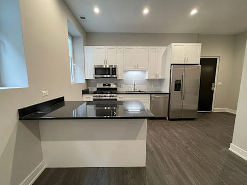 A modern kitchen with a black countertop and stainless steel appliances.