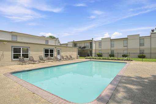 A swimming pool in front of a building with a clear blue sky.