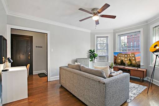 A living room with a grey couch and a ceiling fan.