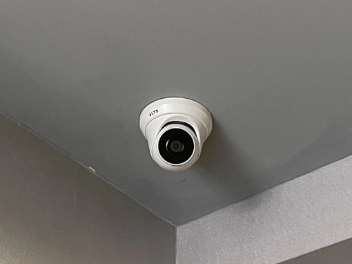 A security camera is mounted on a grey wall.