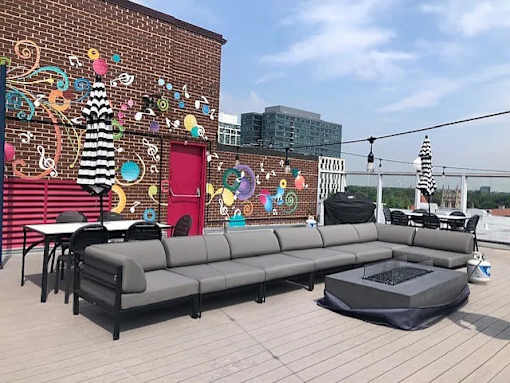 A patio with a grey sofa and a table with a black tablecloth on it.
