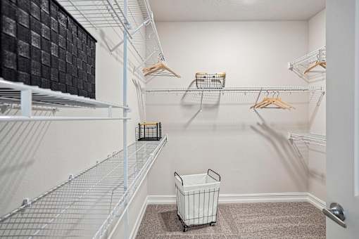 A white closet with a basket on the floor.