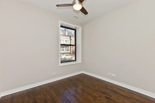 A room with a ceiling fan and a window showing a cityscape.