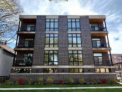 A modern brick building with large windows and balconies.