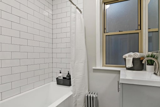 a white bathroom with a window and a tub and a sink