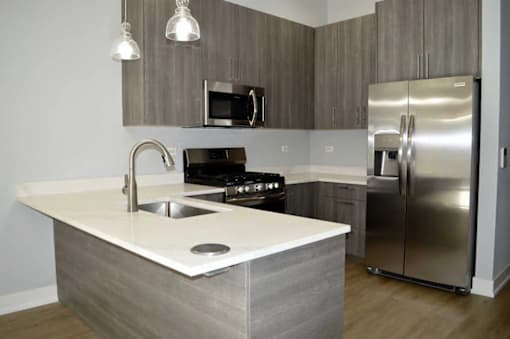 A modern kitchen with a stainless steel refrigerator and a white countertop.