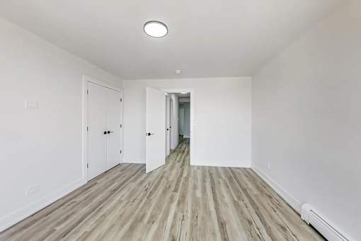 A long hallway with white walls and wood flooring.