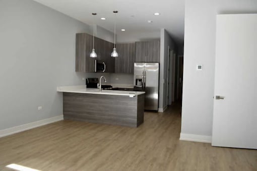 A kitchen with a refrigerator, sink, and cabinets.