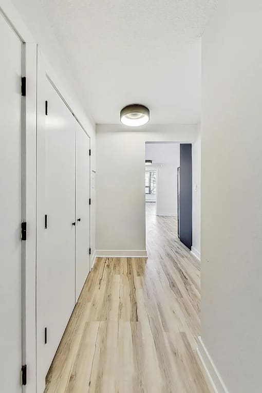 A long hallway with white walls and wood flooring.