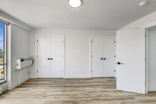 A room with white doors and a window with a view of the city.