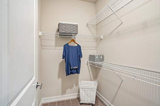 A blue shirt hanging on a hanger in a closet.