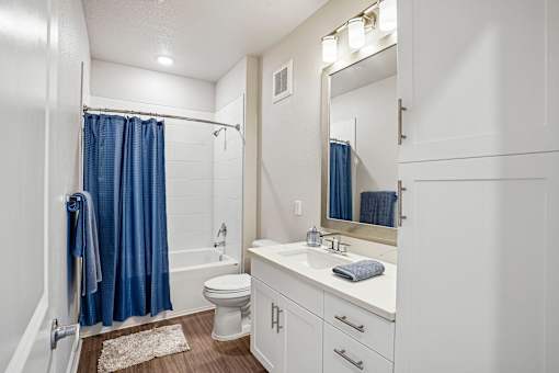 A white bathroom with a blue shower curtain.