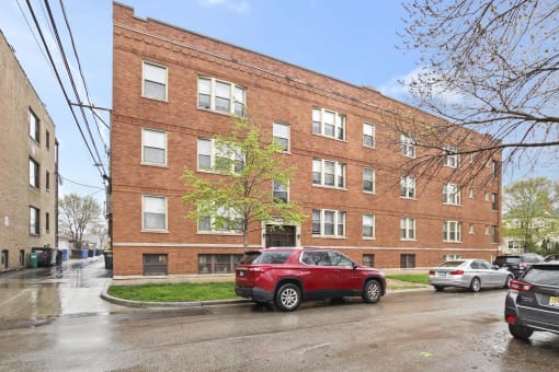 a red brick apartment building with a red car parked in front