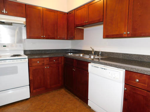 A kitchen with brown cabinets and a white dishwasher.