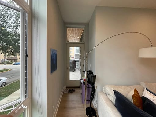 A living room with a white couch and a purple vacuum cleaner.