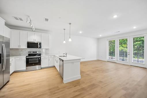 A modern kitchen with wooden floors and white cabinetry.