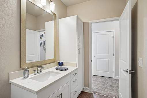 A bathroom with a sink, mirror, and a white door.