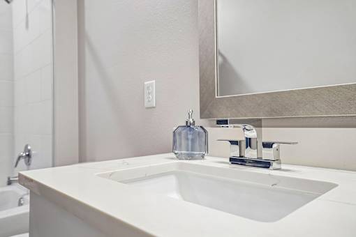 A white sink in a bathroom with a mirror above it.