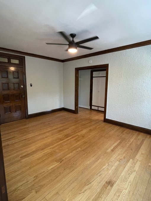 an empty living room with wood floors and a ceiling fan