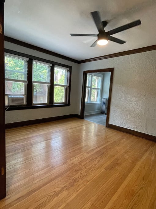 an empty living room with wood floors and a ceiling fan