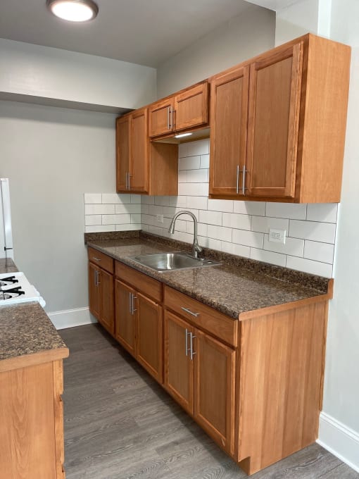 an empty kitchen with wooden cabinets and granite counter top