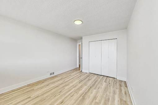 A room with a white door and wooden flooring.