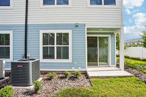 A blue house with a grey air conditioner in front.