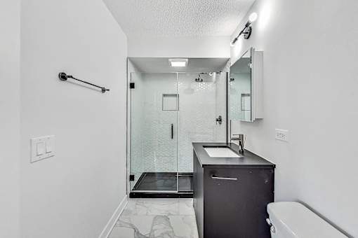 A bathroom with a sink, mirror, and shower.