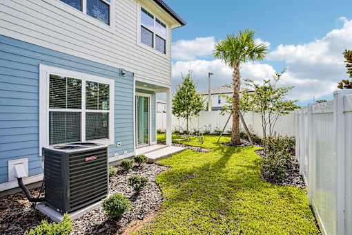 A house with a blue siding and a palm tree in the yard.