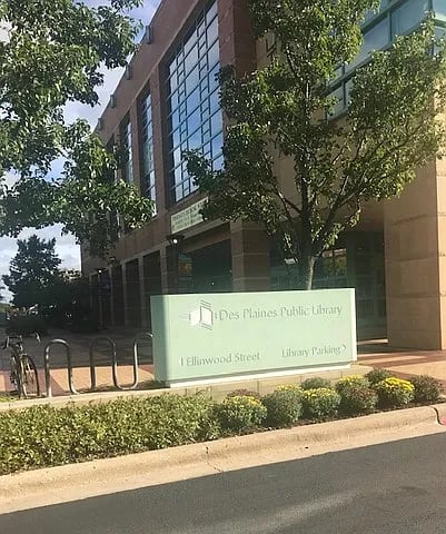A sign for the Des Plaines Public Library is in front of a building.