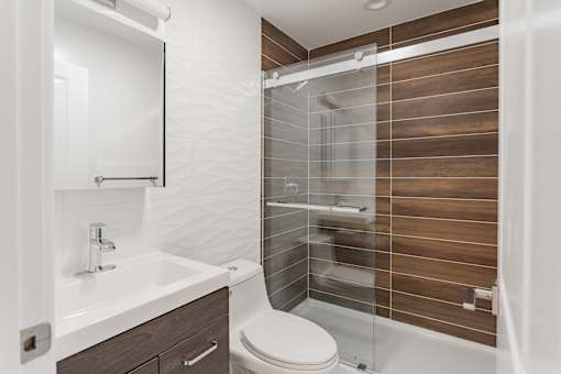 A modern bathroom with a walk-in shower and a white sink.
