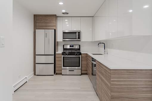 A modern kitchen with a refrigerator, microwave, oven, and sink.