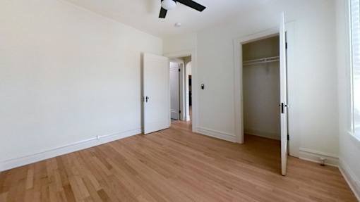 A room with a ceiling fan and wooden flooring.