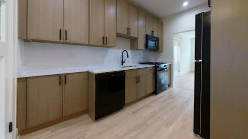 A kitchen with wooden cabinets and black appliances.