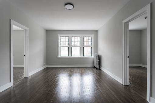 A room with wooden floors and a window with blinds.
