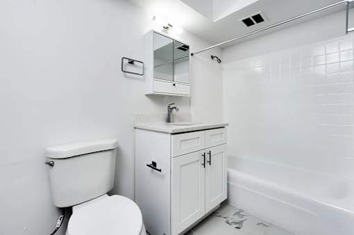 A white toilet sits next to a white cabinet with a mirror above it.