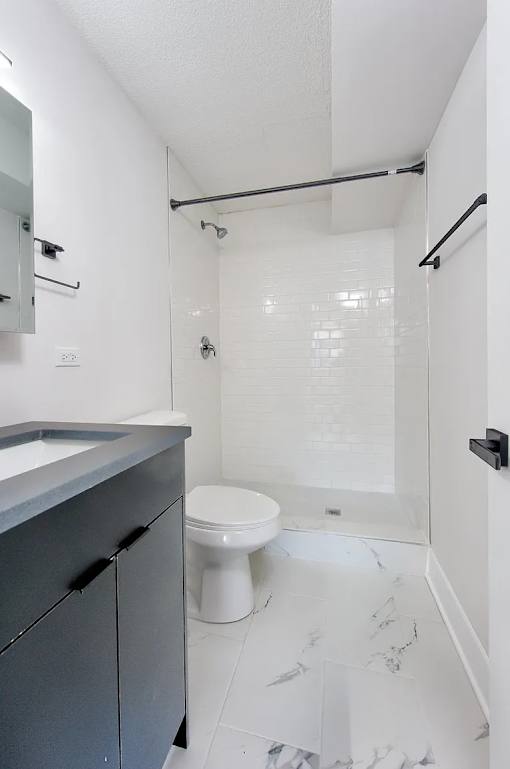 A white toilet sits in a bathroom with a white tile floor.